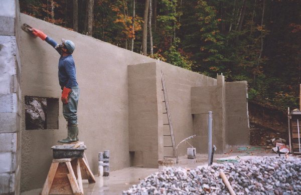  My surface bonded block wall. The house sits on a steep hill. Notice all the buttresses to support the wall. The hole in the wall just under where I'm working is going to be an underground cold box set in the hill.